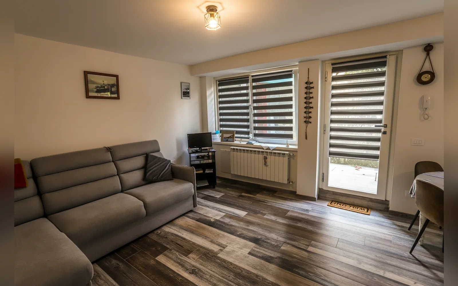 La sala con il divano letto grigio e la portafinestra sul giardino