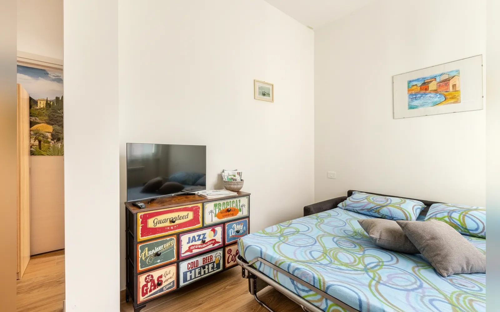 Il divano letto aperto con la cassettiera colorata e la TV