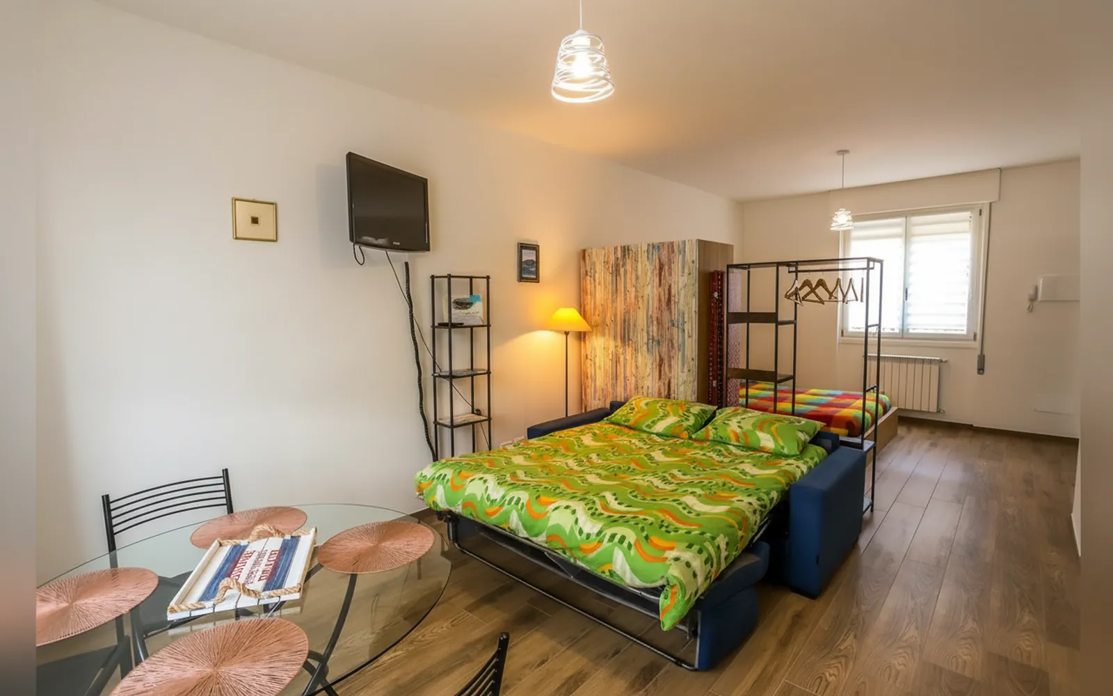 Il loft con il divano letto, il tavolo in vetro e l’appendiabiti in ferro